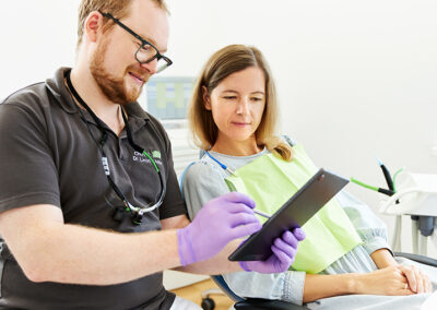 Zahnarzt zeigt Patientin etwas auf einem Tablet