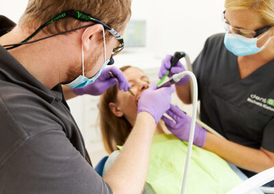 Zahnarzt und Zahnarzthelferin behandeln Patientin