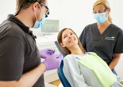 Patientin im Gespräch mit dem Arzt und der Zahnarzthelferin