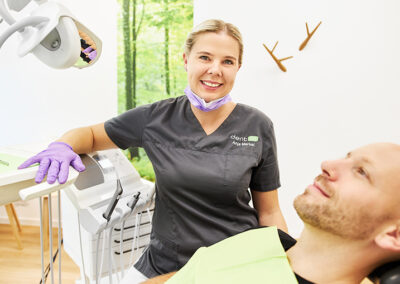 Zahnarzthelferin lächelt vor Ihr ein zufriedenen blickender Patient